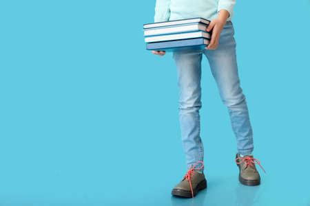 Cute little girl with books on color background