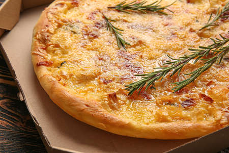 Cardboard box with tasty pizza on wooden background, closeupの写真素材