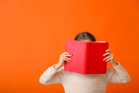 Cute little girl with book on color backgroundの写真素材