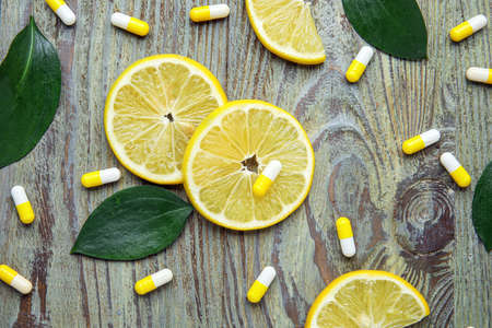 Vitamin C pills and lemon slices on wooden backgroundの写真素材