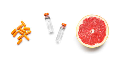 Bottles with vitamin C, pills and grapefruit on white backgroundの写真素材