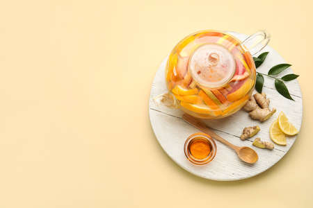 Composition with teapot of tasty ginger tea and ingredients on color backgroundの写真素材