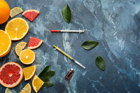 Ampule with vitamin C, syringes and citrus fruits on color backgroundの写真素材