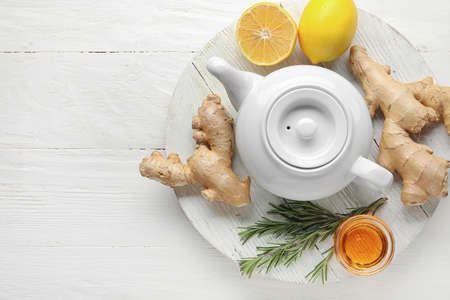 Composition with teapot of tasty ginger tea and ingredients on light wooden backgroundの写真素材