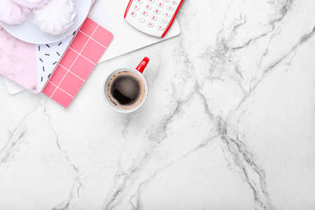 Cup of coffee, notebooks, calculator and tasty marshmallows on light backgroundの写真素材