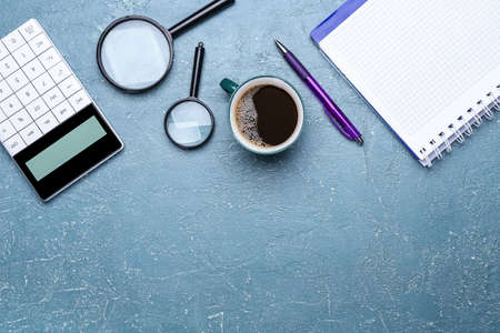 Cup of coffee, notebook, magnifiers, pen and calculator on color backgroundの写真素材