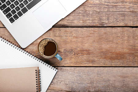Cup of coffee, notebooks and laptop on wooden backgroundの写真素材
