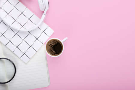 Cup of coffee, magnifier, headphones and notebooks on color backgroundの写真素材