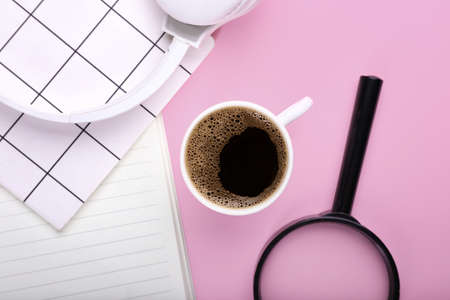Cup of coffee, magnifier, headphones and notebooks on color backgroundの写真素材