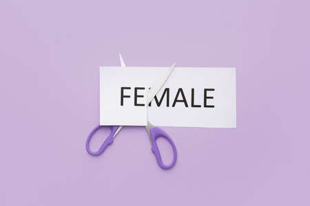 Cutting of paper sheet with word FEMALE on color background. Concept of transgenderの写真素材