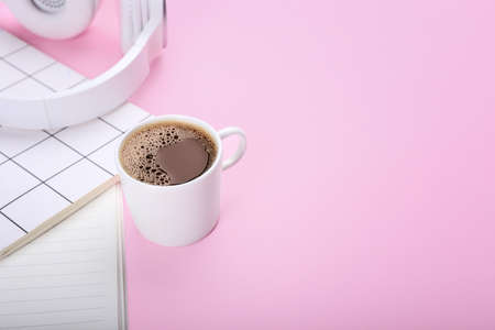 Cup of coffee, headphones and notebooks on color backgroundの写真素材