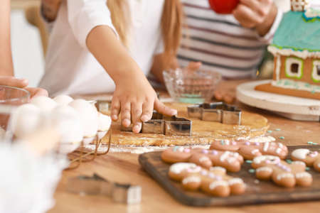 Family making tasty gingerbread cookies in kitchen on Christmas eve
