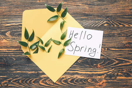 Paper sheet with text HELLO SPRING and envelope on wooden backgroundの写真素材