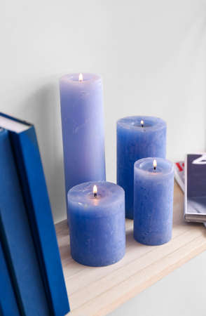 Shelf with burning candles hanging on light wall, closeupの写真素材