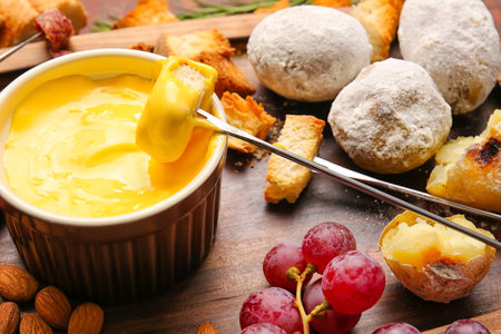 Stick with crouton dipped into cheese fondue on wooden backgroundの写真素材