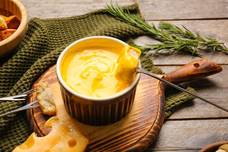 Stick with crouton dipped into cheese fondue on wooden backgroundの写真素材