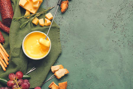 Cheese fondue and different snacks on color backgroundの写真素材