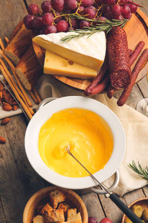 Cheese fondue and different snacks on wooden backgroundの写真素材