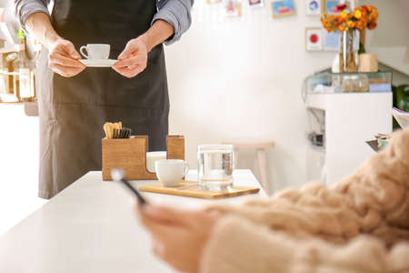 Barista bringing hot espresso for visitor in cafeの写真素材