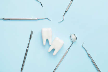 Dentist's tools and plastic teeth on color background