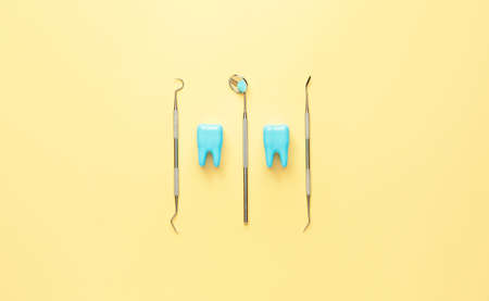 Dentist's tools and plastic teeth on color background