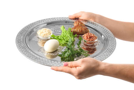 Female hands with Passover Seder plate and traditional food on white background