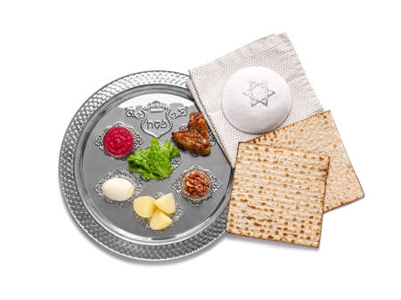 Passover Seder plate with traditional food and Jewish cap on white background
