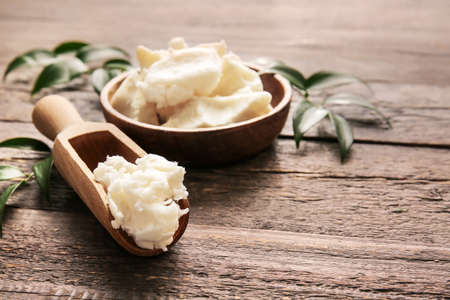 Plate and scoop with shea butter on wooden backgroundの写真素材