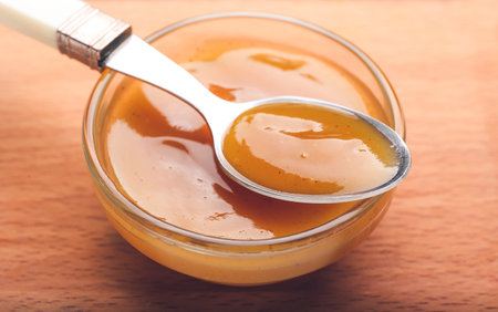 Bowl and spoon with tasty apricot jam on wooden backgroundの写真素材