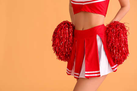 Beautiful young cheerleader on color background