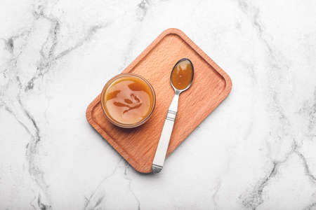 Bowl and spoon with tasty apricot jam on light backgroundの写真素材