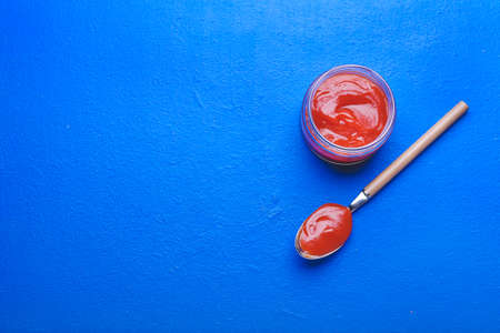 Jar and spoon with tasty ketchup on color backgroundの写真素材