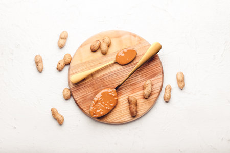 Spoons with tasty peanut butter on light backgroundの写真素材