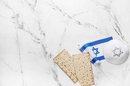 Jewish flatbread matza for Passover, cap and flag of Israel on light background