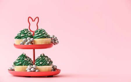 Stand with tasty Christmas cupcakes on color backgroundの写真素材