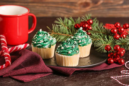 Plate with tasty Christmas cupcakes on tableの写真素材