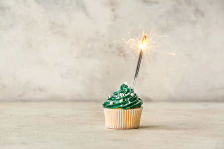 Tasty Christmas cupcake on table