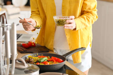 Young housewife cooking in kitchen at home