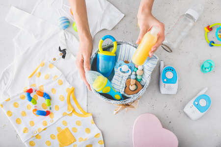 Woman with baby shower gifts on light background
