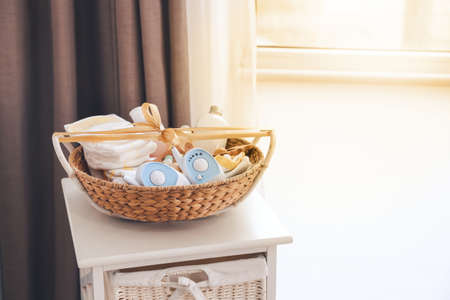 Wicker basket with gifts for baby on table in room