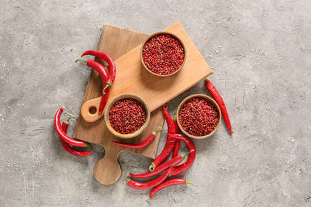Bowls with red peppercorns on gray background