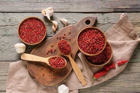 Bowls and spoons with red peppercorns on wooden backgroundの写真素材