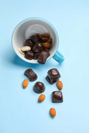 Cup with sweet chocolate candies and nuts on color backgroundの写真素材