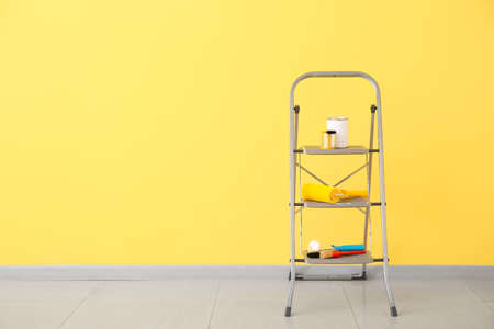 Ladder with cans of paints and tools near color wallの写真素材