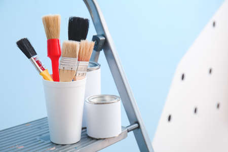 Ladder with cans of paints and brushes near color wall, closeupの写真素材