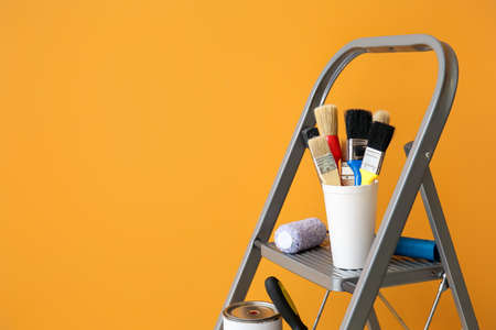 Ladder with brushes and roller near color wall