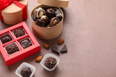 Boxes with sweet chocolate candies on color background