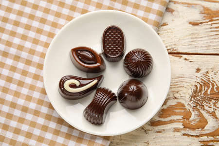 Plate with sweet chocolate candies on table