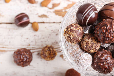 Glass bowl with sweet chocolate candies on wooden backgroundの写真素材