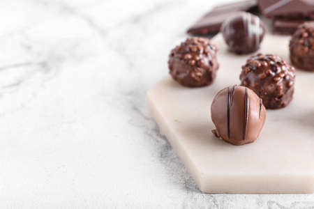 Board with sweet chocolate candies on light backgroundの写真素材